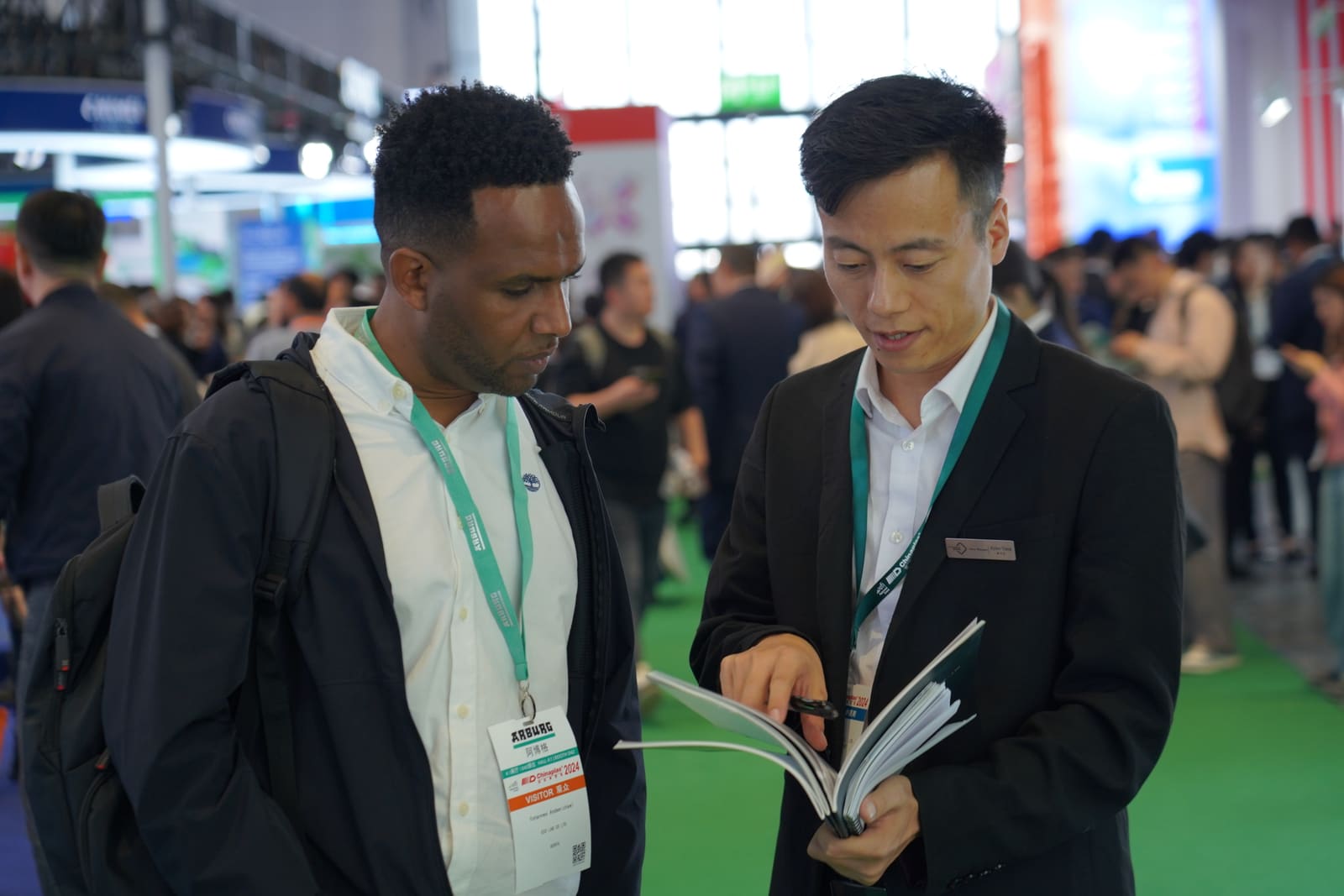 RUUIPON team reviewing silicone mold brochure with a buyer at Chinaplas exhibition
